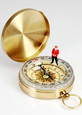 A compass with a tiny person standing on it, representing the Creative Problem-Solving Lab run by Jessica Kavanagh of Creative Ark